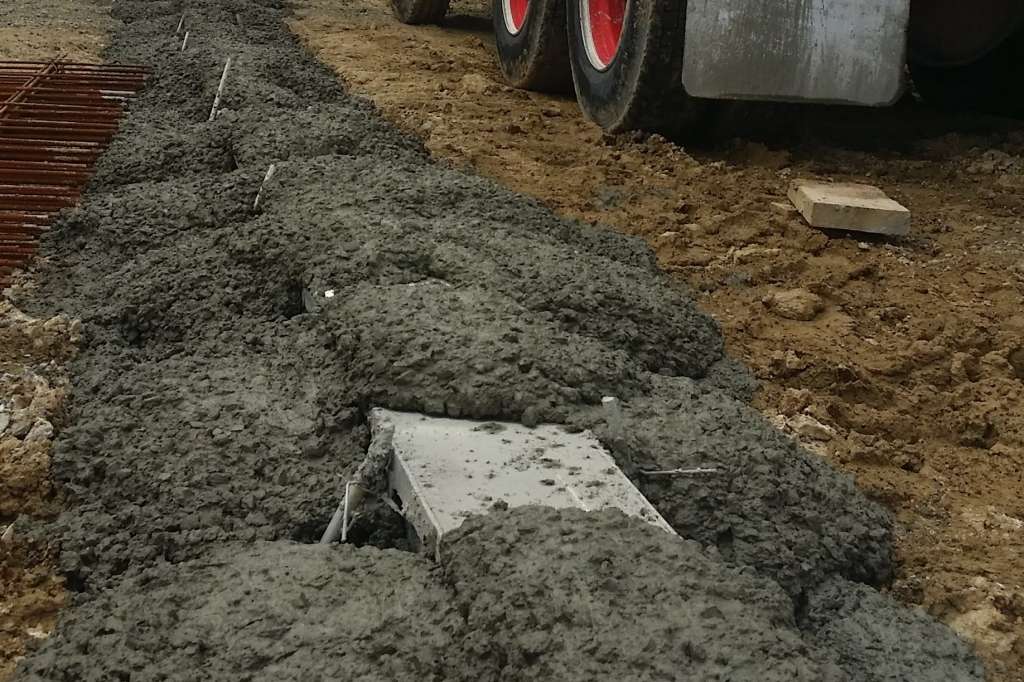 wet Concrete being dumped on top of the poly during the concrete pour to prevent "float". The poly inserts are quite robust and withstand this loading. 